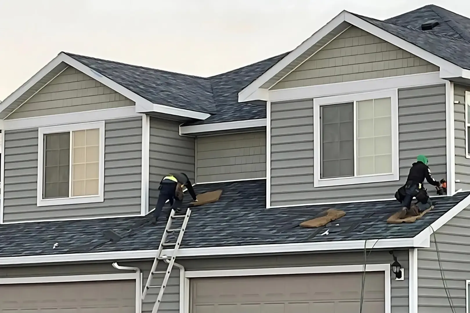 Roofing crew installing new architectural shingles on a two-story home
